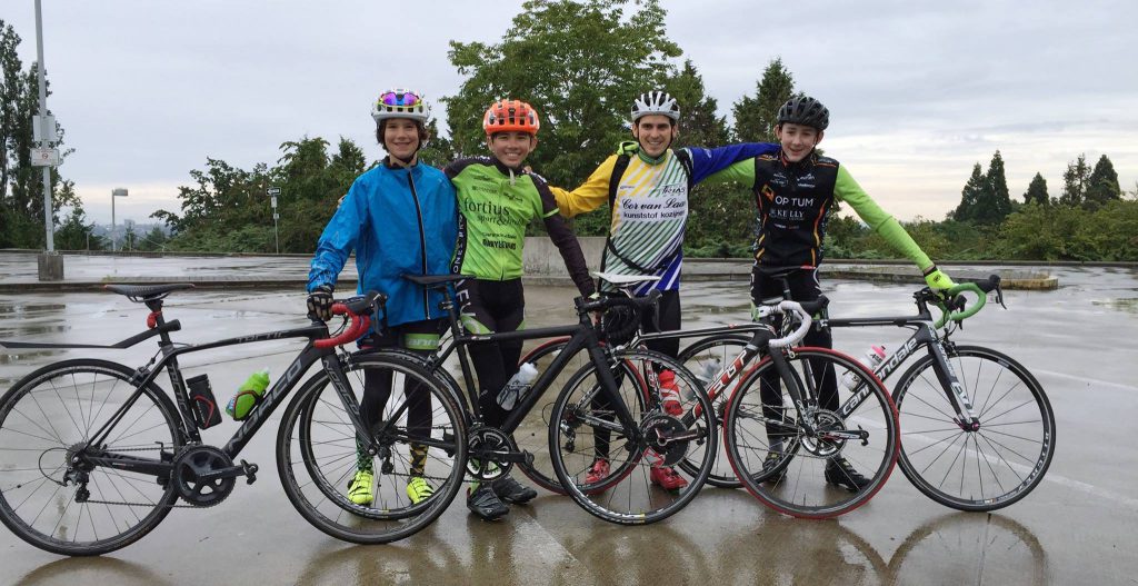 Young riders in rain jackets with their road bikes on a grey day